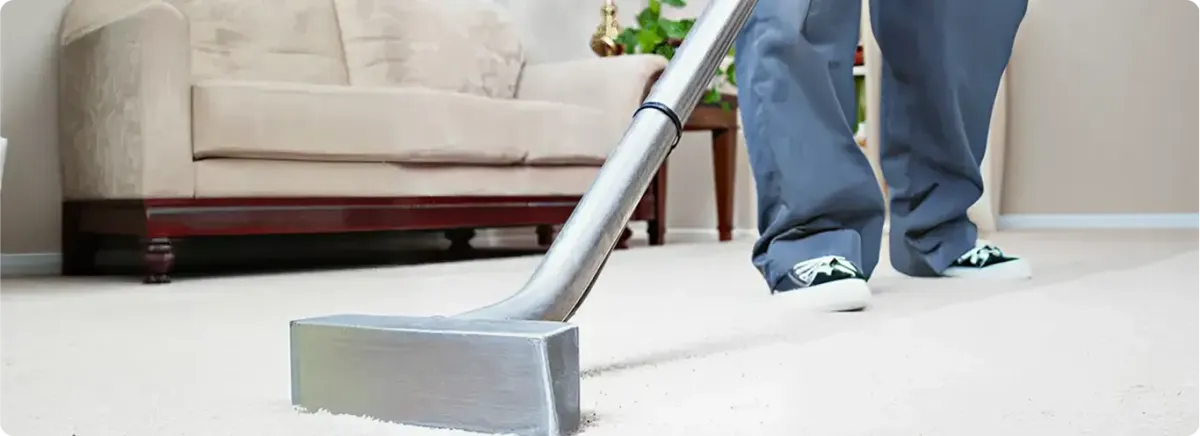 Carpet cleaning technician using a hot-water extraction wand on a light-colored carpet in a living room, Norfolk, VA.